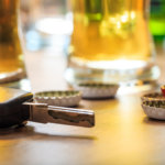 Car key, drinks and bottle caps signifying DWI charges.