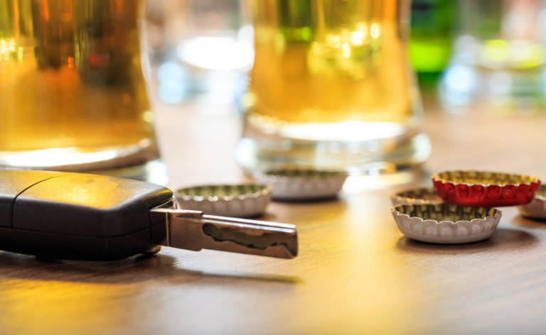 Car key, drinks and bottle caps signifying DWI charges.