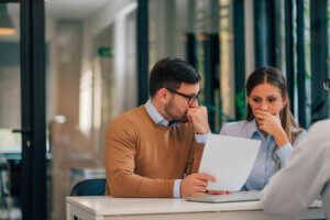 Portrait of a couple with financial problems looking at document in financial adviser's office.