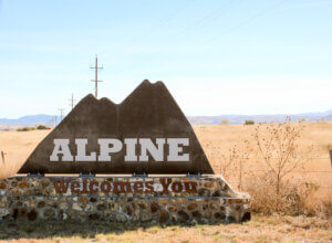 welcoming sign into the town of alpine texas in far west texas made of stone and rock